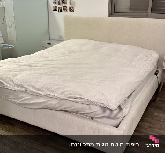 מיטה עם מצעים לבנים בחדר שינה